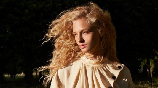 Woman with blonde curly hair blowing in the wind