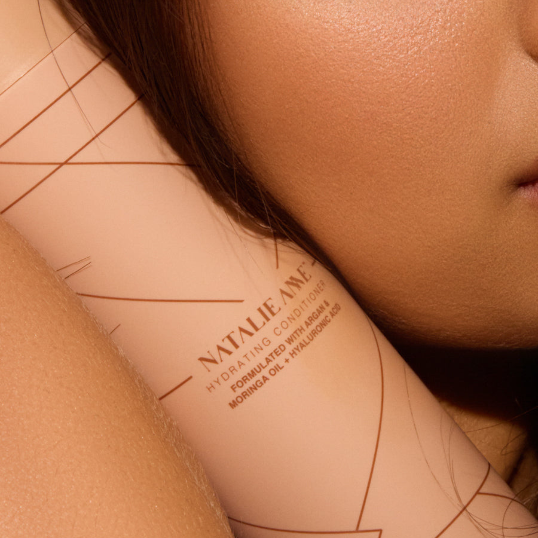Natalie Anne Hydrating Conditioner Bottle held near womans cheek