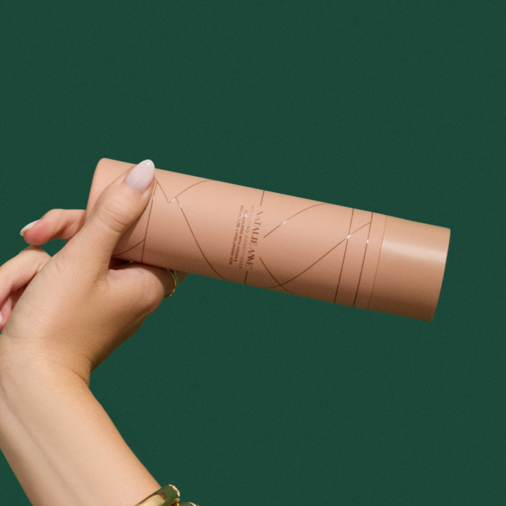 Natalie Anne Hydrating Conditioner held in hand with green background