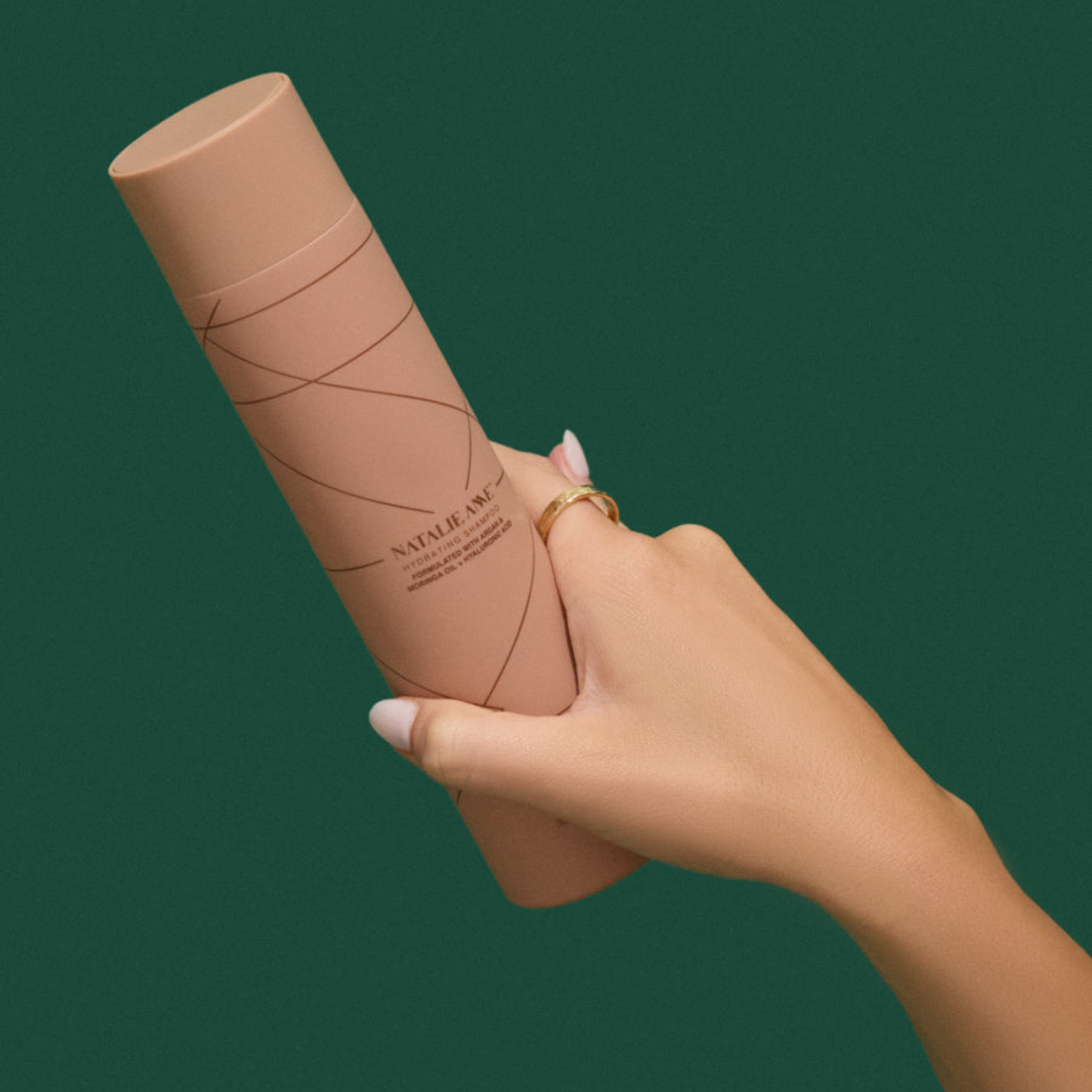 Natalie Anne Hydrating Shampoo held in hand with gold ring