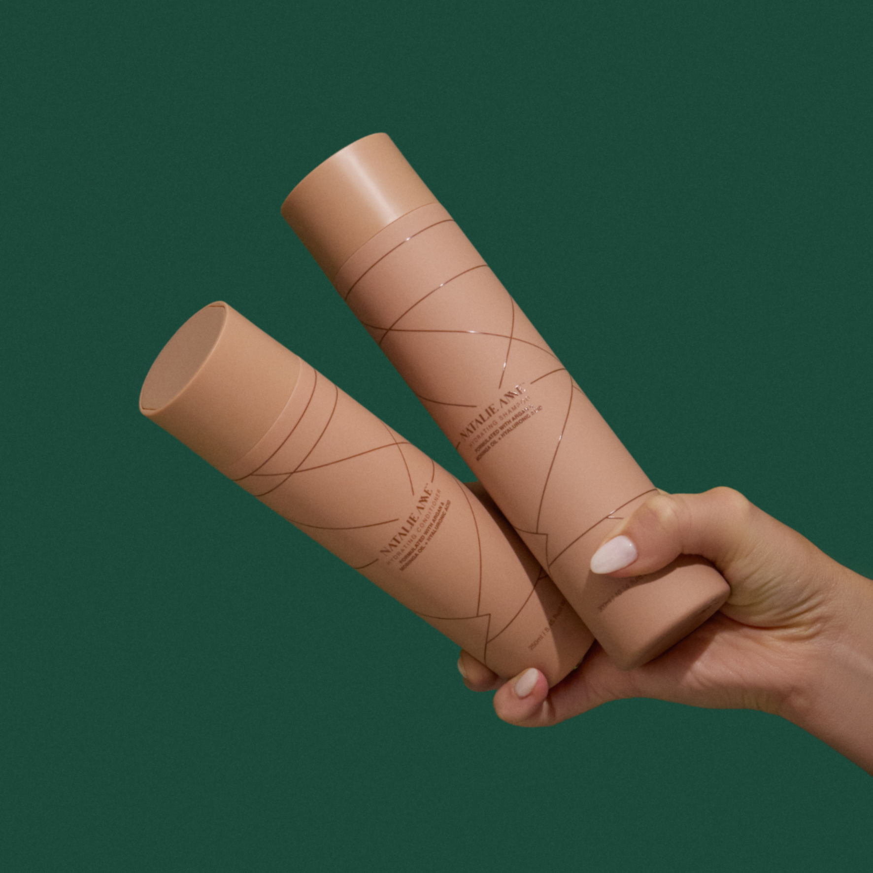 Natalie Anne Shampoo and Conditioner held in hand on green background
