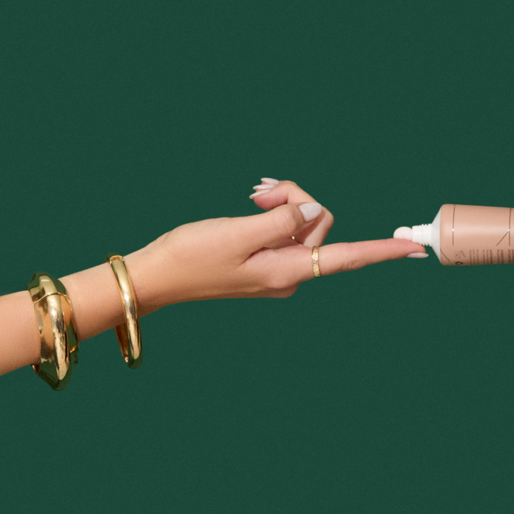 Natalie Anne Prep & Play All-In-One Cream being squeezed onto finger tip on green background