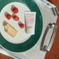 Tube of evo ritual salvation repairing shampoo on a plate with raspberries and a cracker, on a tray.
